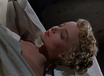 Movie still from “House of Wax” (1953), directed by André De Toth – A woman laying on the ground with her eyes closed; Close Up shot, High angle