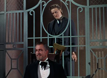 Movie still from “House of Wax” (1953), directed by André De Toth – A man in a suit standing next to another man in a suit and tie; Medium shot, Low angle