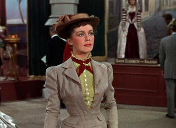 Movie still from “House of Wax” (1953), directed by André De Toth – A woman wearing a suit and hat in a movie scene; Medium shot, Low angle