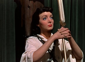 Movie still from “House of Wax” (1953), directed by André De Toth – A woman holding a bow and arrow in her hands; Medium shot, High angle