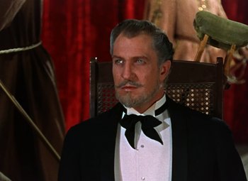 Movie still from “House of Wax” (1953), directed by André De Toth – A man in a tuxedo sitting in a wooden chair; Medium shot, Low angle