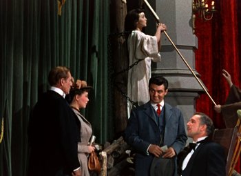 Movie still from “House of Wax” (1953), directed by André De Toth – A group of people standing in front of a curtain; Wide shot, Low angle