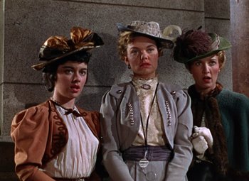 Movie still from “House of Wax” (1953), directed by André De Toth – A group of three women wearing hats and coats; Medium shot, Low angle