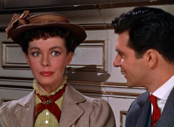 Movie still from “House of Wax” (1953), directed by André De Toth – A woman wearing a hat standing next to a man wearing a suit; Close Up shot, Over the shoulder angle