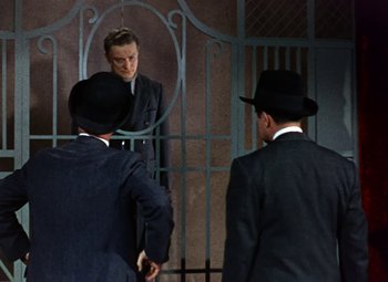 Movie still from “House of Wax” (1953), directed by André De Toth – A man in a suit and a black hat is looking in the mirror; Medium shot, Low angle