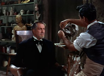 Movie still from “House of Wax” (1953), directed by André De Toth – A man sitting in a chair in front of a statue; Medium shot, Over the shoulder angle