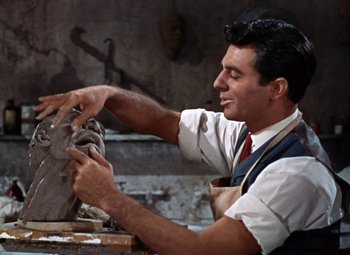 Movie still from “House of Wax” (1953), directed by André De Toth – A man in an apron is working on a sculpture; Close Up shot, Over the shoulder angle
