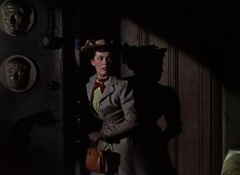 Movie still from “House of Wax” (1953), directed by André De Toth – A woman standing in front of a wooden door; Medium shot, Low angle