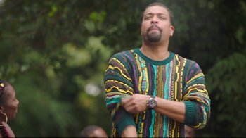 Movie still from “How High 2” (2019), directed by Bruce Leddy – A man in a colorful sweater standing in front of a tree; Medium shot, Low angle