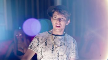 Movie still from “How High 2” (2019), directed by Bruce Leddy – A young man wearing a hat and a chain necklace; Close Up shot, Over the shoulder angle