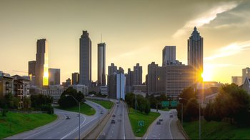 Movie still from “How High 2” (2019), directed by Bruce Leddy – A view of a city skyline at sunset with cars driving on the road; Extreme Wide shot, High angle