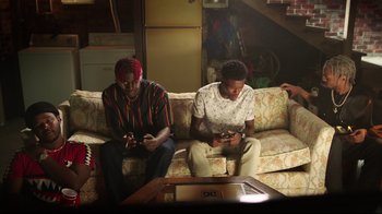 Movie still from “How High 2” (2019), directed by Bruce Leddy – Two men sitting on a couch looking at their phones; Medium shot, High angle