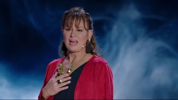 Movie still from “How High 2” (2019), directed by Bruce Leddy – A woman in a black top and red jacket holding a microphone; Medium shot, Over the shoulder angle