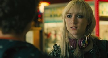 Movie still from “How I Live Now” (2013), directed by Kevin Macdonald – A woman with pink headphones is standing in front of a man; Close Up shot, Over the shoulder angle