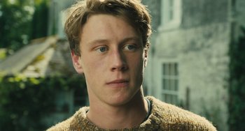 Movie still from “How I Live Now” (2013), directed by Kevin Macdonald – A young man wearing a sweater is looking at the camera; Close Up shot, Low angle