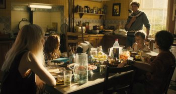Movie still from “How I Live Now” (2013), directed by Kevin Macdonald – A group of people sitting around a table with food; Wide shot, High angle