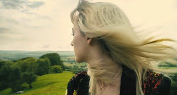 Movie still from “How I Live Now” (2013), directed by Kevin Macdonald – A woman with long blonde hair blowing in the wind on top of a hill; Close Up shot, Low angle