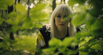 Movie still from “How I Live Now” (2013), directed by Kevin Macdonald – A woman with blonde hair is standing in the woods; Close Up shot, High angle