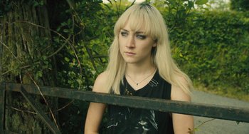 Movie still from “How I Live Now” (2013), directed by Kevin Macdonald – A woman with blonde hair and a black top; Close Up shot, High angle