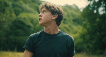 Movie still from “How I Live Now” (2013), directed by Kevin Macdonald – A young man looking up into the sky; Close Up shot, Low angle