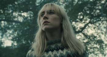 Movie still from “How I Live Now” (2013), directed by Kevin Macdonald – A woman with long blonde hair wearing a sweater looking up; Close Up shot, Low angle
