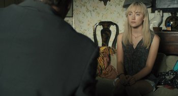 Movie still from “How I Live Now” (2013), directed by Kevin Macdonald – A woman sitting in front of a man in front of a chair; Medium shot, Over the shoulder angle