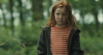 Movie still from “How I Live Now” (2013), directed by Kevin Macdonald – A young girl in a striped shirt and a jacket; Medium shot, Low angle