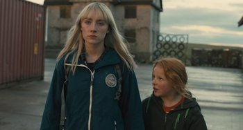 Movie still from “How I Live Now” (2013), directed by Kevin Macdonald – Two young people standing next to each other on the street; Close Up shot, Over the shoulder angle