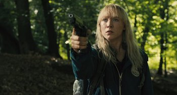 Movie still from “How I Live Now” (2013), directed by Kevin Macdonald – A woman holding a gun in a forest; Close Up shot, Over the shoulder angle