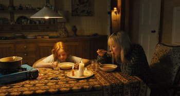 Movie still from “How I Live Now” (2013), directed by Kevin Macdonald – Two women sitting at a dinner table with candles; Wide shot, High angle