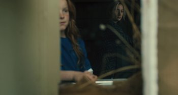 Movie still from “How I Live Now” (2013), directed by Kevin Macdonald – A woman is looking in the mirror in front of a window; Close Up shot, Over the shoulder angle