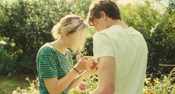 Movie still from “How I Live Now” (2013), directed by Kevin Macdonald – A man and a woman holding hands in a field; Medium shot, Over the shoulder angle