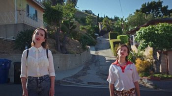 Movie still from “How It Ends” (2021), directed by Daryl Wein – Two young women walking down a street in a residential area; Medium shot, High angle