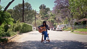 Movie still from “How It Ends” (2021), directed by Daryl Wein – A man sitting on a chair playing a guitar; Wide shot, High angle