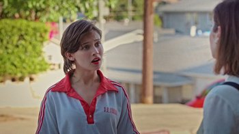 Movie still from “How It Ends” (2021), directed by Daryl Wein – A woman in a red and white shirt is standing on a sidewalk; Close Up shot, Over the shoulder angle