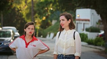 Movie still from “How It Ends” (2021), directed by Daryl Wein – Two young women standing on a sidewalk in front of a building; Medium shot, High angle