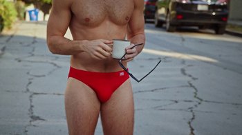Movie still from “How It Ends” (2021), directed by Daryl Wein – A man in red swim trunks holding a cup; Medium shot, Overhead angle
