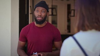 Movie still from “How It Ends” (2021), directed by Daryl Wein – A man in a red t - shirt is holding a nintendo wii game controller; Medium shot, Over the shoulder angle