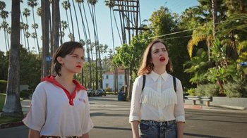 Movie still from “How It Ends” (2021), directed by Daryl Wein – Two young women standing on the side of the street; Medium shot, Low angle