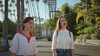 Movie still from “How It Ends” (2021), directed by Daryl Wein – Two young women standing on the side of the street; Medium shot, Low angle