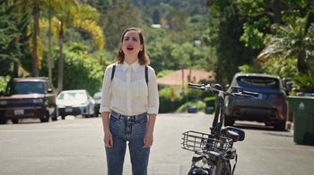 Movie still from “How It Ends” (2021), directed by Daryl Wein – A woman standing next to a bike on the side of the road; Medium shot, Over the shoulder angle