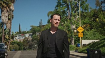 Movie still from “How It Ends” (2021), directed by Daryl Wein – A man in a black suit standing on the side of the road; Medium shot, Low angle
