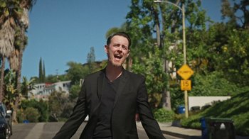 Movie still from “How It Ends” (2021), directed by Daryl Wein – A man wearing a suit and tie standing on the street; Medium shot, Low angle