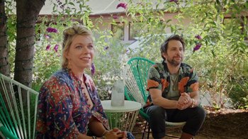 Movie still from “How It Ends” (2021), directed by Daryl Wein – A man and a woman sitting on chairs in front of trees; Medium shot, Low angle