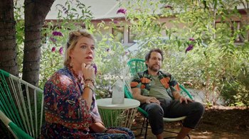 Movie still from “How It Ends” (2021), directed by Daryl Wein – A man and a woman sitting on a chair in a garden; Medium shot, Low angle