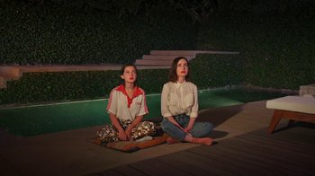 Movie still from “How It Ends” (2021), directed by Daryl Wein – Two young women sitting on the ground next to each other; Wide shot, High angle