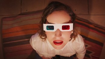 Movie still from “How It Ends” (2021), directed by Daryl Wein – A woman wearing a pair of 3 - d glasses; Close Up shot, Overhead angle