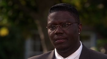 Movie still from “How to Be a Player” (1997), directed by Lionel C. Martin – A person wearing glasses and a suit; Close Up shot, High angle