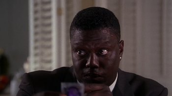 Movie still from “How to Be a Player” (1997), directed by Lionel C. Martin – A man in a black suit looking at a camera; Close Up shot, High angle