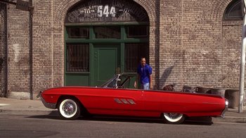 Movie still from “How to Be a Player” (1997), directed by Lionel C. Martin – A man standing next to an old red car; Wide shot, Low angle